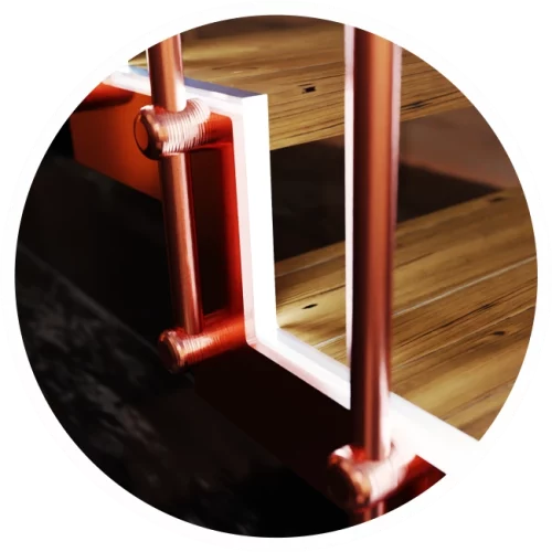 Detalle de uniones de pasamanos en color cobre es escalera de interior con luz led metal madera