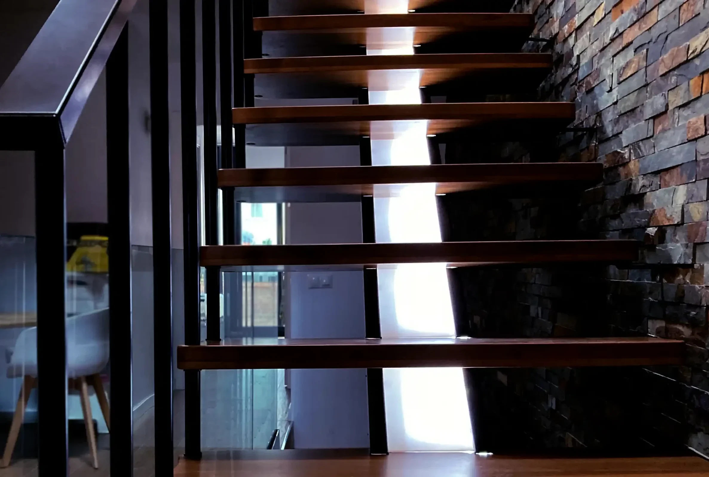 Escalera divine con luz horizontal a lo largo de la zanca central con peldaños de madera y estructura metalica